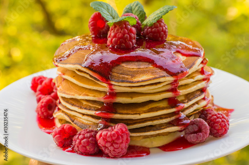 Pancakes with raspberry jam and fresh berries. Wooden background. Close-up