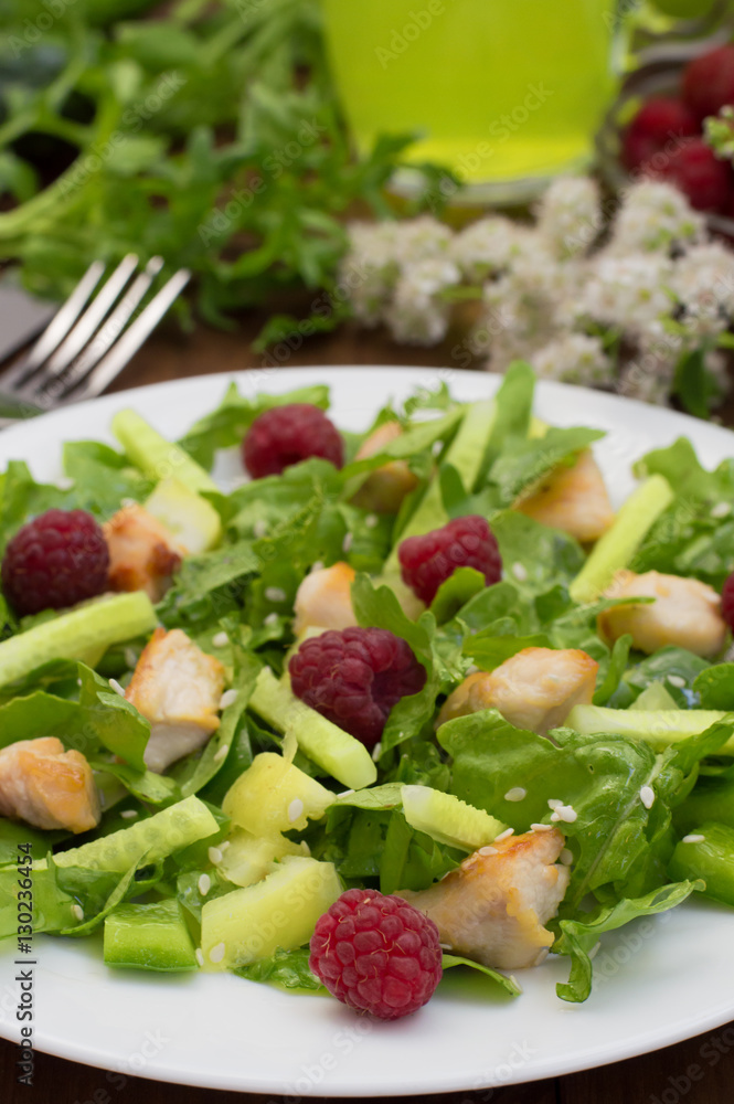 Salad with raspberries, arugula, cucumber, paprika, roasted chicken and sesame. Wooden background. Close-up