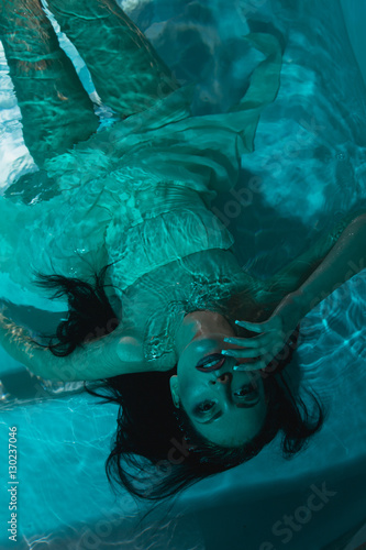 beautiful girl in a dress dives under the water