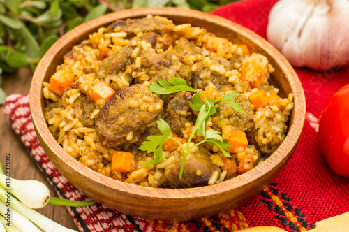Uzbek pilaf - a dish consisting of rice and meat. At the traditional wooden background. Close-up