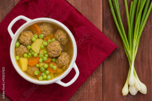 Soup with meatballs, carrots and peas. Wooden rustic background. Top view. Close-up