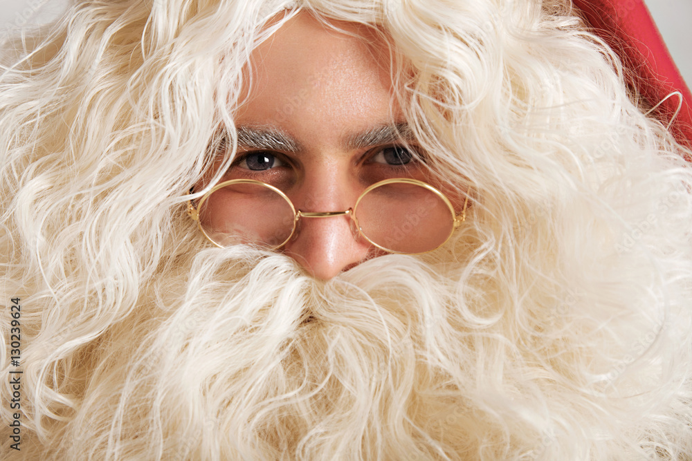 Cute Santa with greyish blue eyes and golden glasses, close up portrait