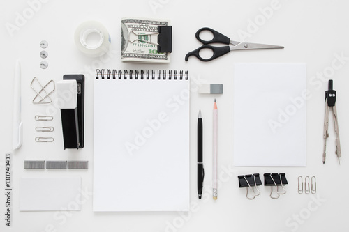 Set of black and white office supplies flat lay. Top view on various stationery on desk: notepads, pencils, scissors, stapler, clip, pins, pen, pencil and bundle of money. Business accessories mocup photo