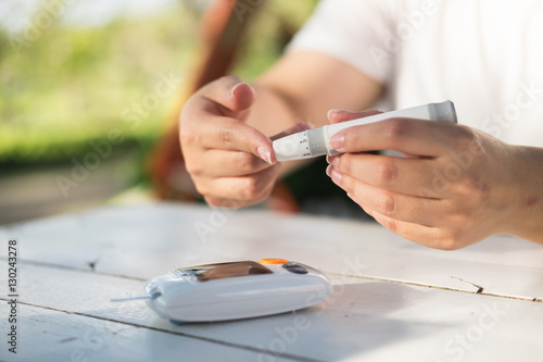 Close up of asian woman hands using lancet on finger to check bl