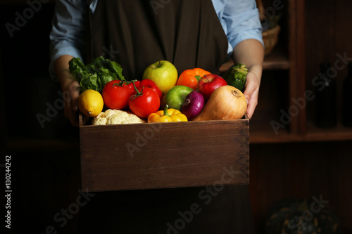 Fototapeta Naklejka Na Ścianę i Meble -  Human hands holding wooden box with different fruits and vegetables closeup