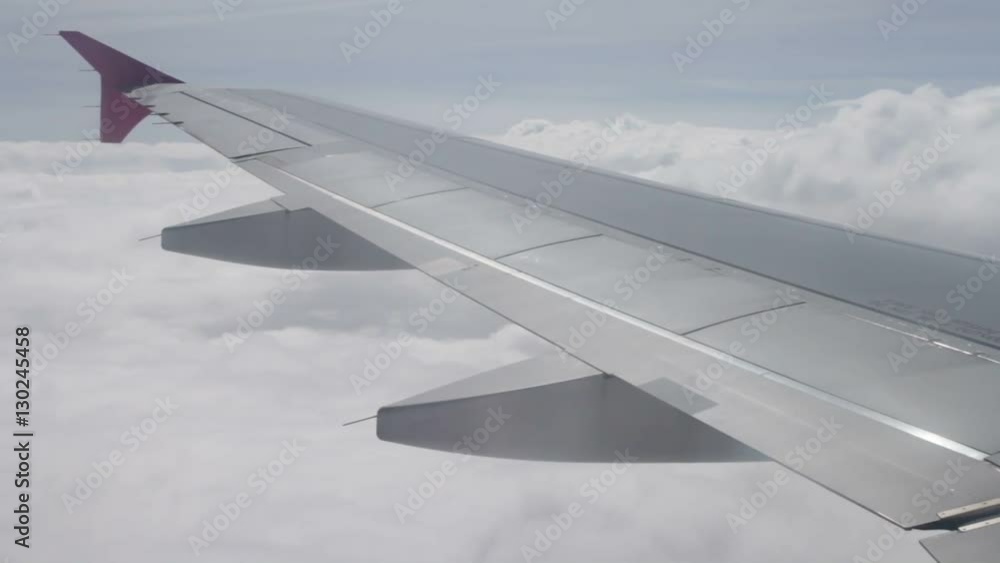 Wing of airplane flying above the clouds in sky Wing of airplane flying above the clouds in sky