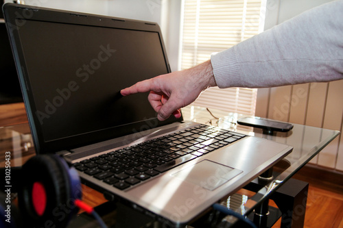 Male hand forefinger about to tap a laptop screen te home