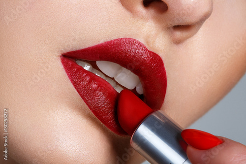 Close up portrait model applying dark red lipstick.. Professional fashion retro make-up.