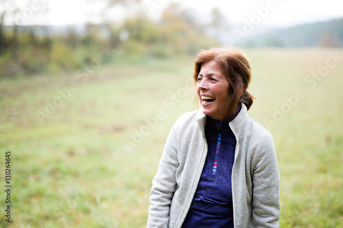 Senior runner resting outside in sunny autumn nature, laughing.