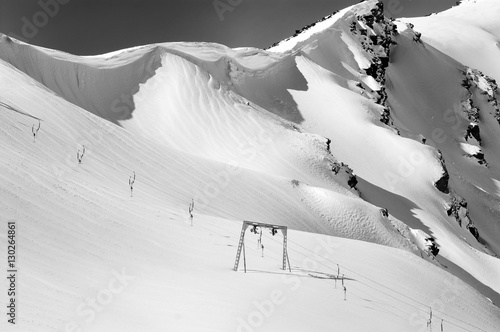Fotografie Black and white view on old surface lift and mountains with snow