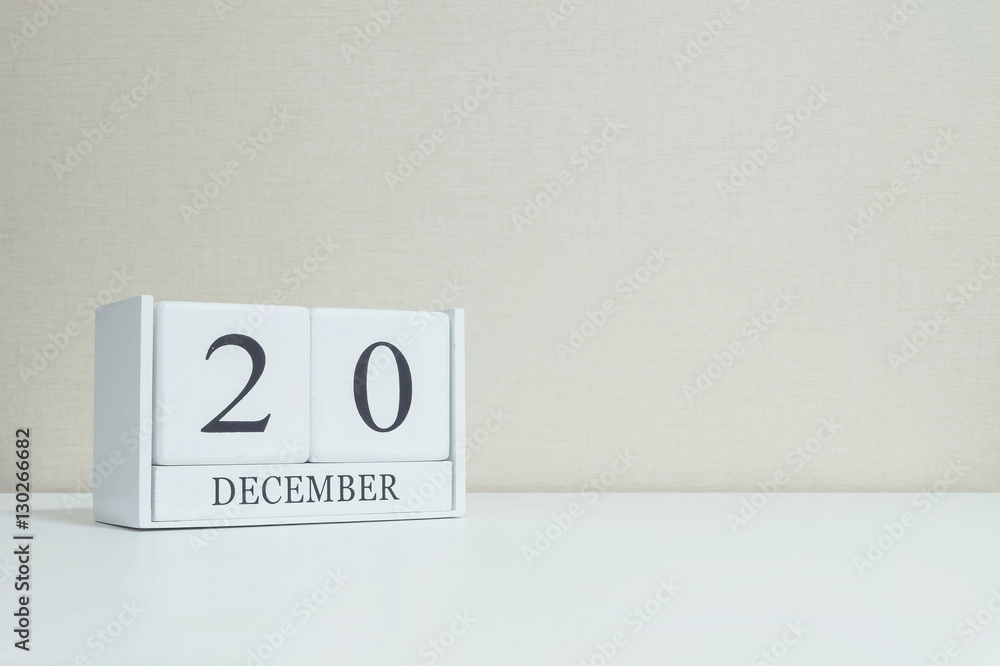 Closeup white wooden calendar with black 20 december word on blurred white wood desk and cream color wallpaper in room textured background with copy space , selective focus at the calendar Closeup white wooden calendar with black 20 december word on blurred white wood desk and cream color wallpaper in room textured background with copy space , selective focus at the calendar