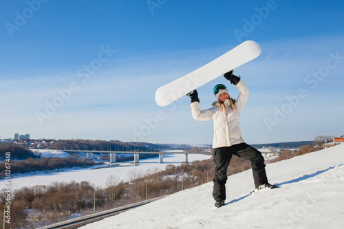 Young woman showing her snowboard as a white empty space