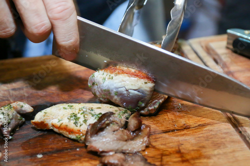 Hand with knife cutting raw fish meat on cutting board for special dish