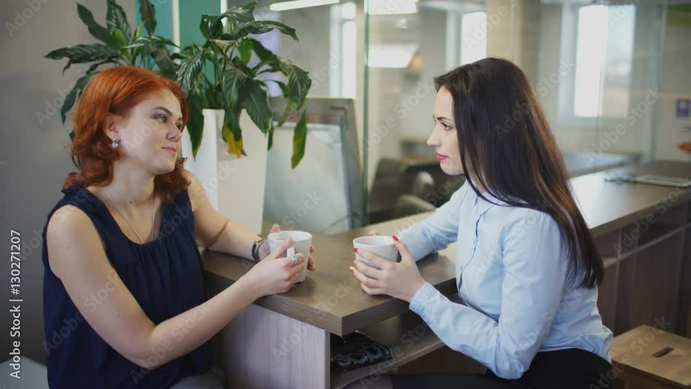 Two women drink coffee speak inside office in break up Two women drink coffee speak inside office in break up