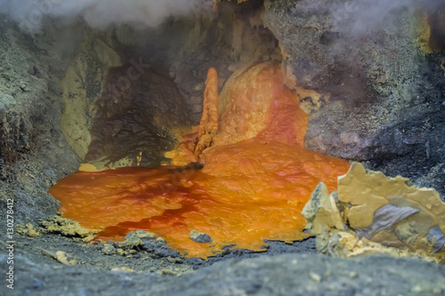 Orange hot lava flows and form puddles on the solidify stone, shrouded in smoke and steam (Indonesia) © alekseev