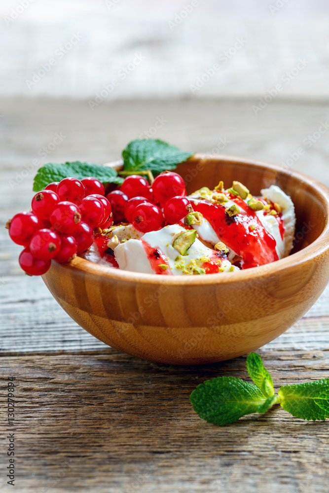 Ice cream with berry sauce and pistachios in a wooden bowl. Ice cream with berry sauce and pistachios in a wooden bowl.