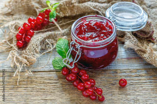 Rustic table with a jar of homemade jam and red currant. photo