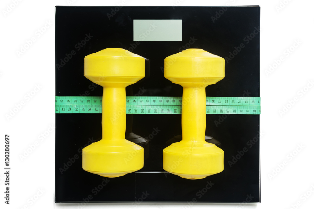 Dumbbells and measure tape lying on the scales Dumbbells and measure tape lying on the scales