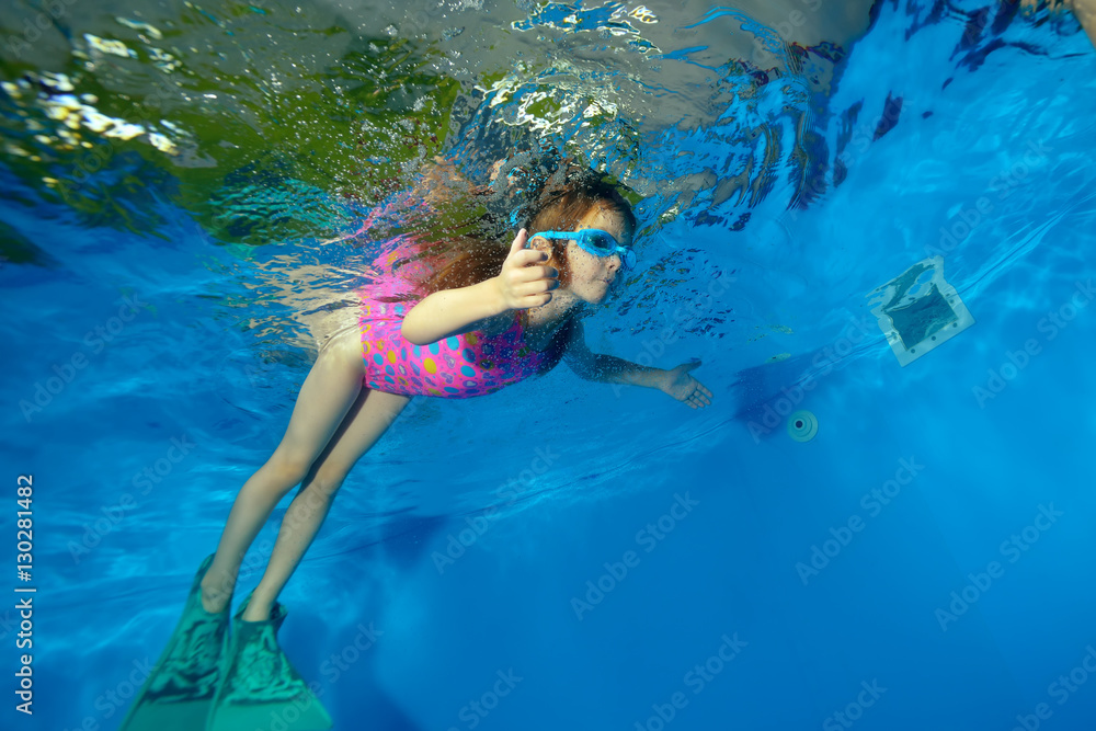 Sports little girl swimming fins underwater in the pool on a blue ...