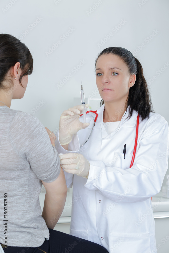woman doctor about to vaccinate her patient with a syringe woman doctor about to vaccinate her patient with a syringe