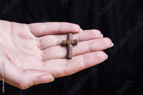 Cross in female hands on a dark background 