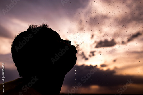 Fototapeta Naklejka Na Ścianę i Meble -  man sprinkles water at sunset