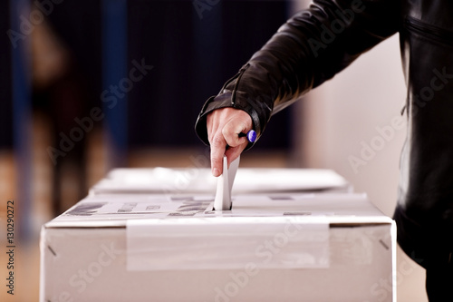 Hand casting a vote into the ballot box photo