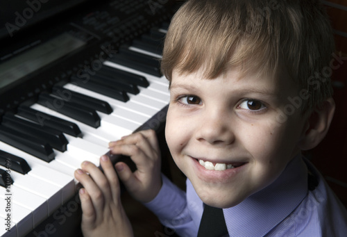 smiling little boy sitting at the piano