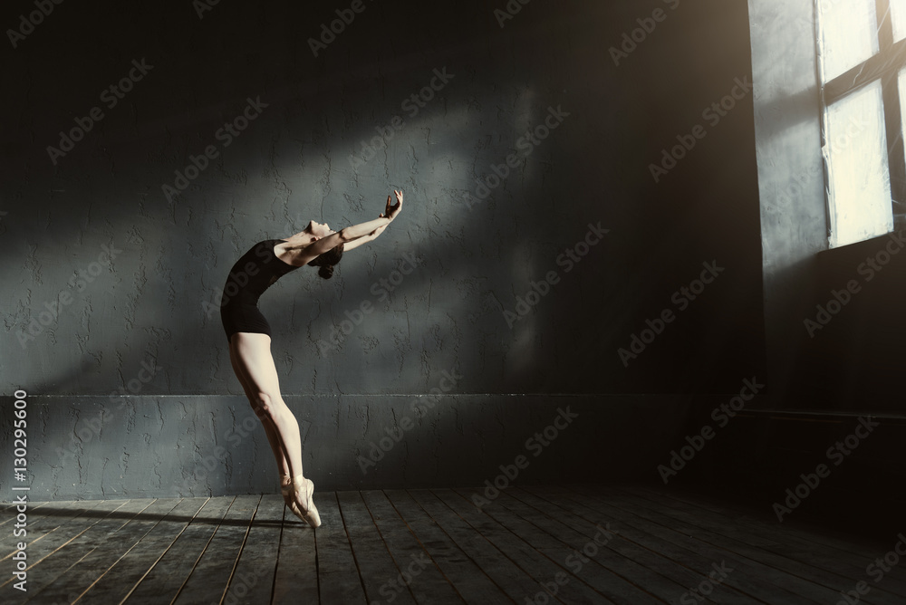 Flexible ballet dancer stretching in the dark lighted studio - obrazy, fototapety, plakaty 
