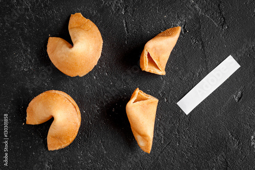 Chinese fortune cookie with prediction on dark background top view