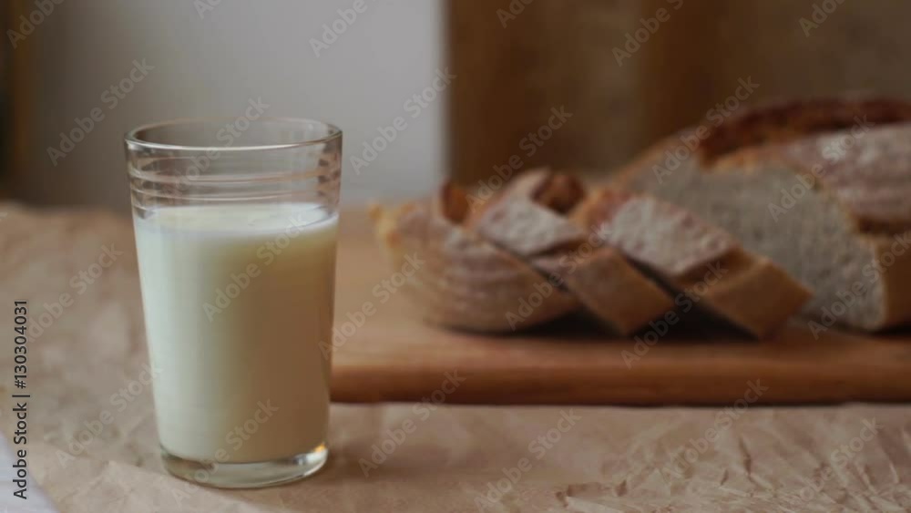 Glass of milk and sliced bread on kitchen table. Dairy product at healthy breakfast. Milk glass and bread slices on cutting board. Milk cup on breakfast table. Breakfast food at morning Glass of milk and sliced bread on kitchen table. Dairy product at healthy breakfast. Milk glass and bread slices on cutting board. Milk cup on breakfast table. Breakfast food at morning