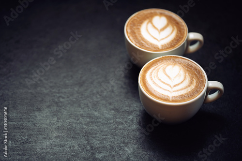 Two cups of coffee on black rustic background
