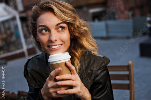 Young beautiful woman drinks coffee on cafe terrace