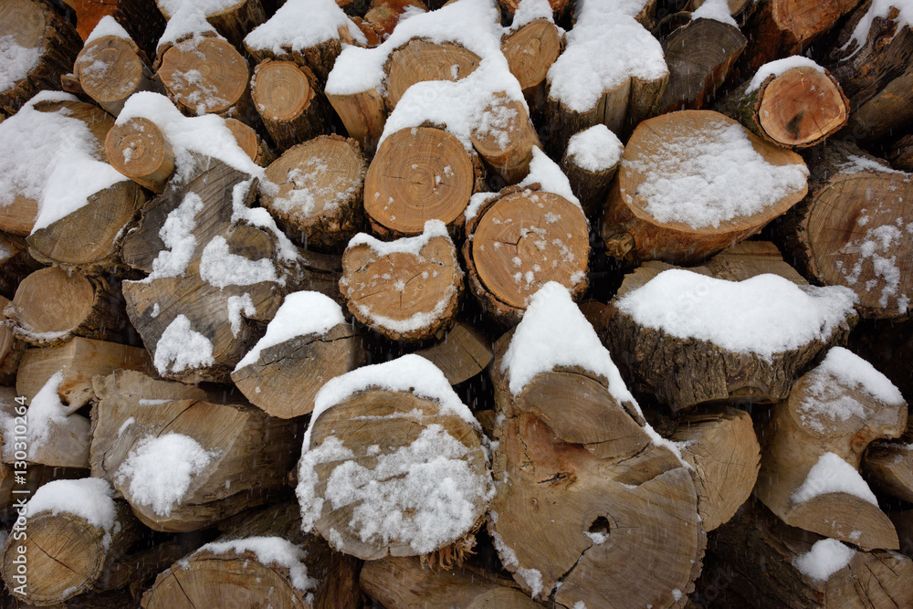 Faces of logs in winter. Woodpile of firewood under snow. Abstract background texture. Faces of logs in winter. Woodpile of firewood under snow. Abstract background texture.