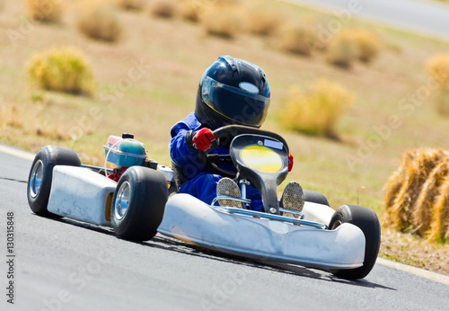 Young kid racing a go cart around a track.