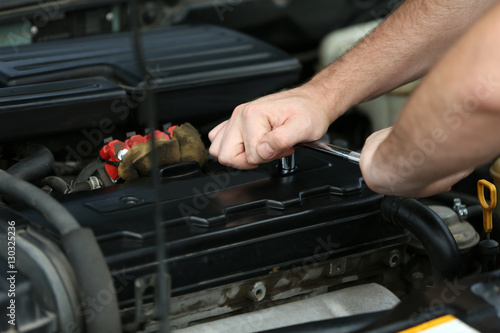 Mechanic hands repairing car in open hood