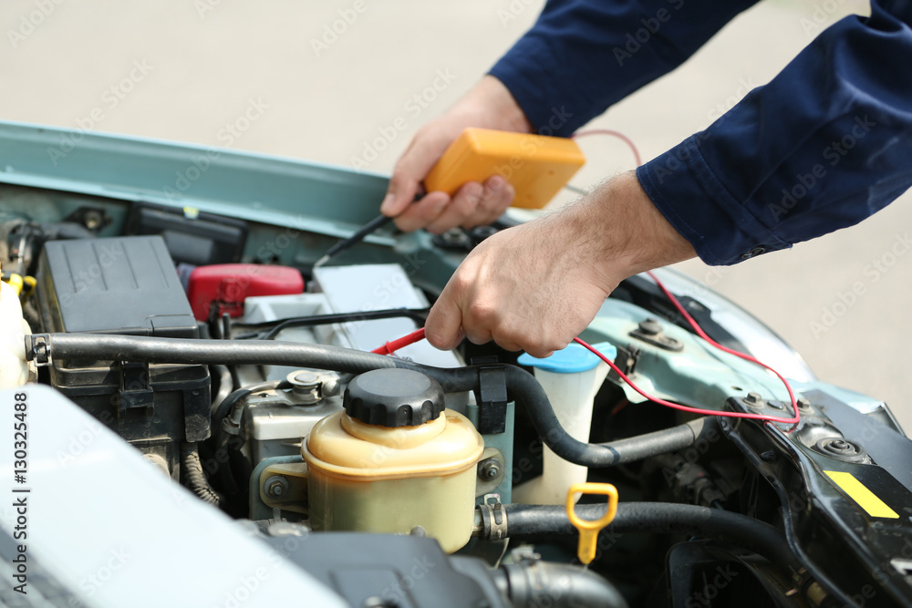 Mechanic hands with scan tool diagnosing car in open hood. Closeup Mechanic hands with scan tool diagnosing car in open hood. Closeup