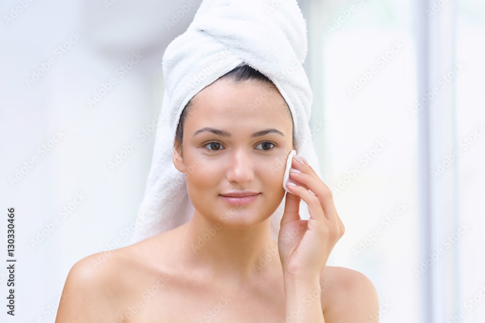 Beautiful girl cleaning face with sponge in front of mirror Beautiful girl cleaning face with sponge in front of mirror