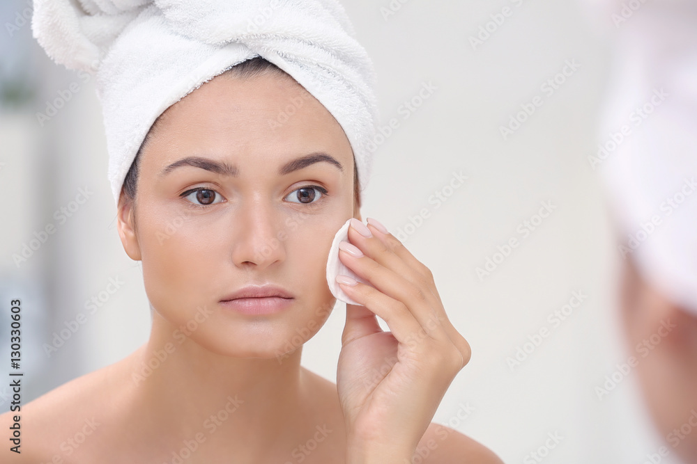 Beautiful girl cleaning face with sponge in front of mirror Beautiful girl cleaning face with sponge in front of mirror