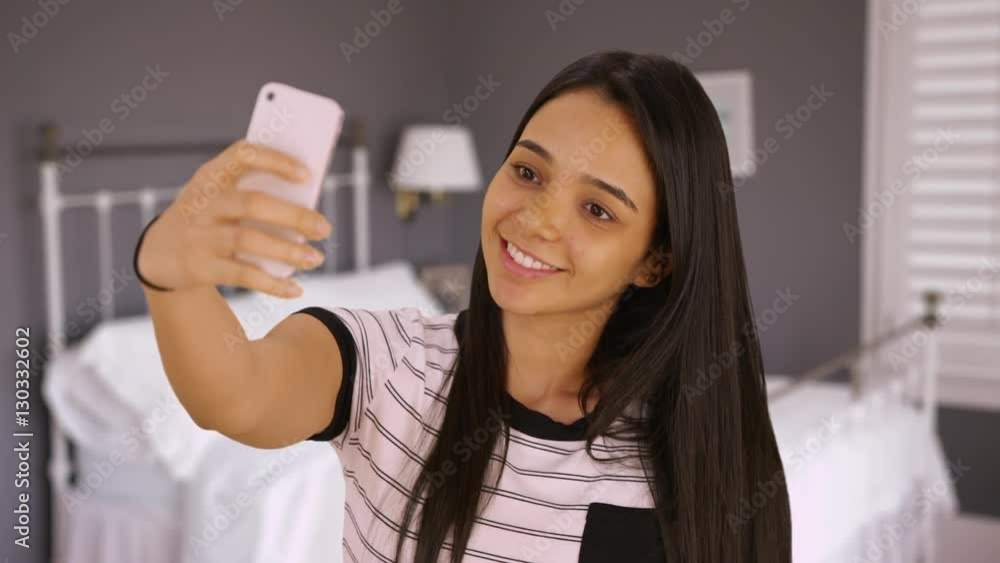 A cute teen takes a selfie in her bedroom. A young girl takes a picture of herself with her smart phone. A cute teen takes a selfie in her bedroom. A young girl takes a picture of herself with her smart phone.