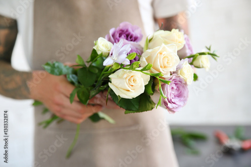 Male florist holding beautiful bouquet at flower shop