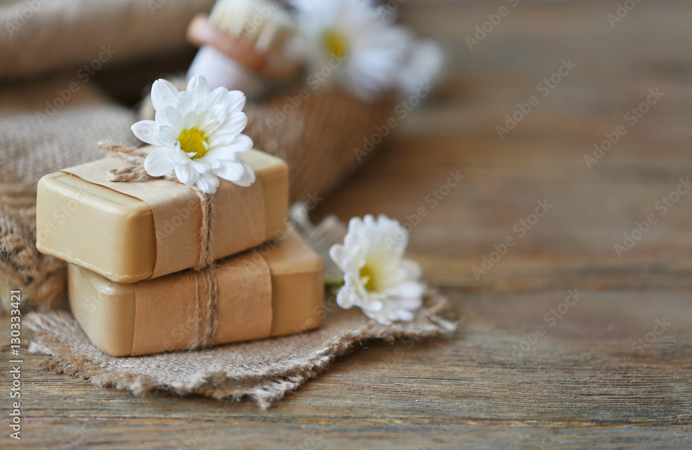 Spa concept. Soap and daisy flowers on wooden table