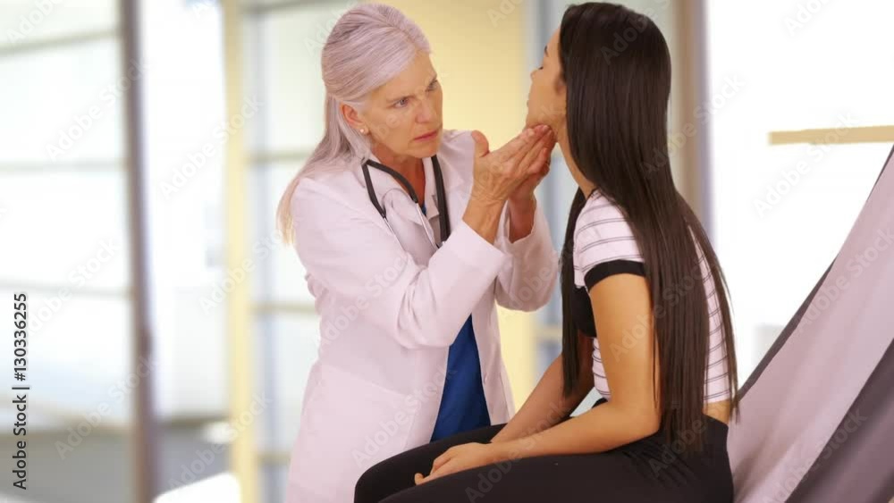 An older doctor gives a check-up to a young girl. A young teen receives her annual check-up. An older doctor gives a check-up to a young girl. A young teen receives her annual check-up.