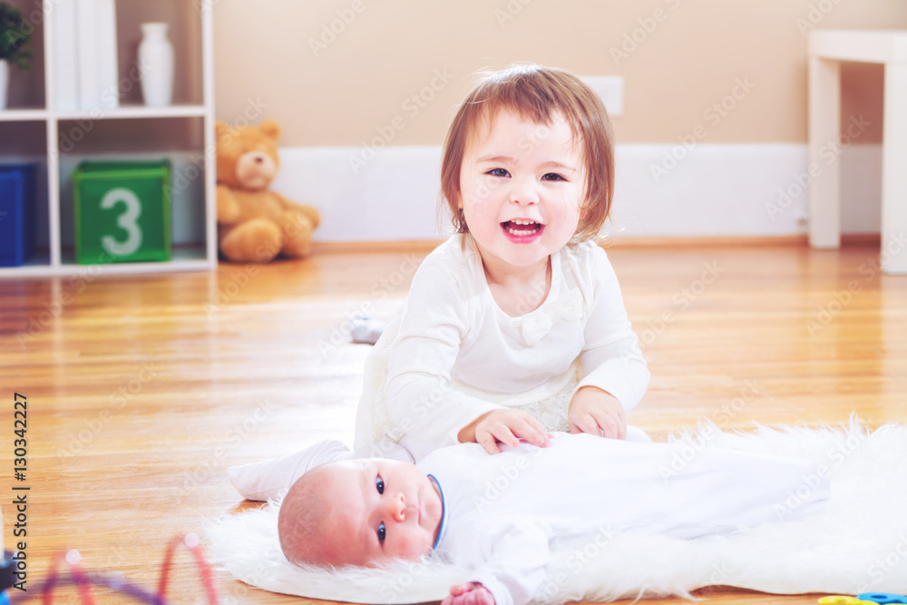 Happy toddler girl with her newborn sister Happy toddler girl with her newborn sister