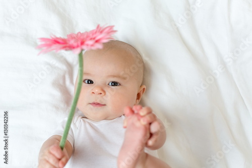 Happy newborn baby girl playing with a flower