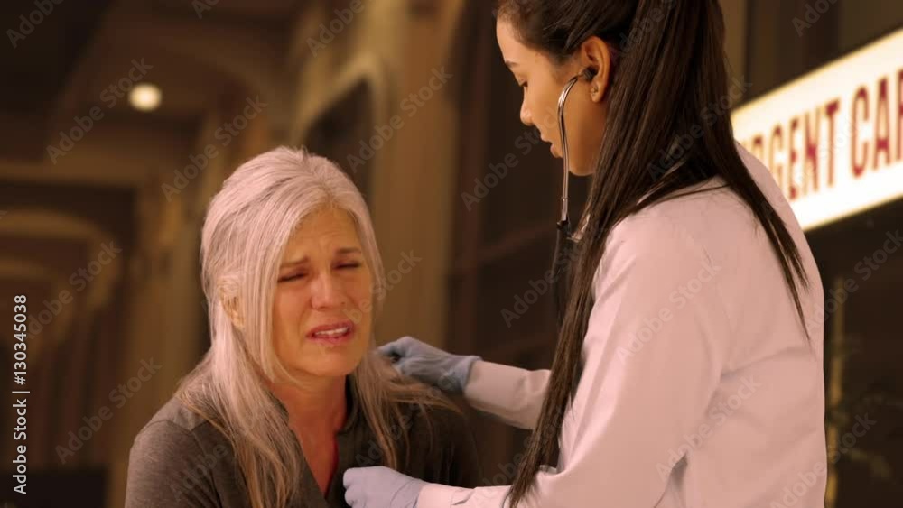 An older woman gets help at an urgent care. A medical professional helps an elderly woman. 