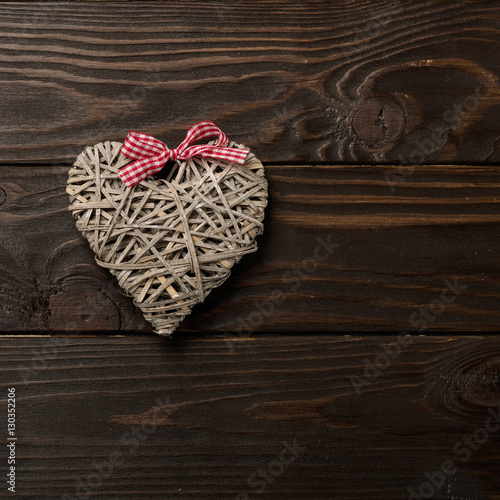 Concept of Valentine's Day. Wicker hearts on dark wooden backgro