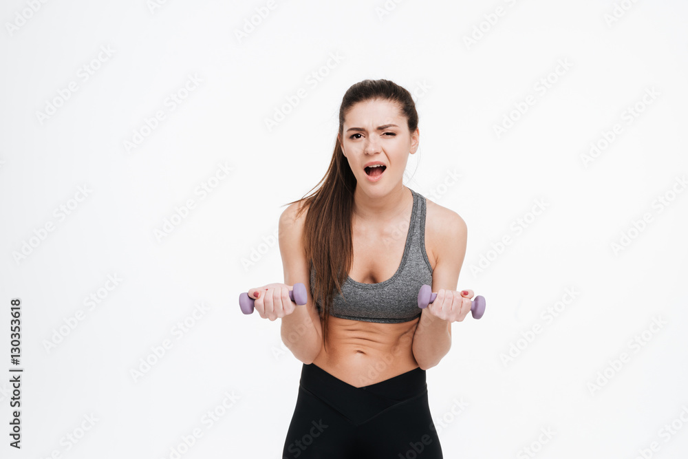 Portrait of a tired sportswoman doing intensive training with dumbbells Portrait of a tired sportswoman doing intensive training with dumbbells