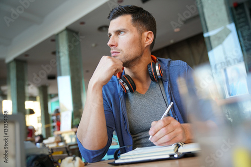 Man sitting in restaurant writing notes on agenda