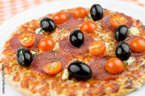 Hot Salami Pizza With Olives And Fresh Cherry Tomatoes On Plaid Tablecloth